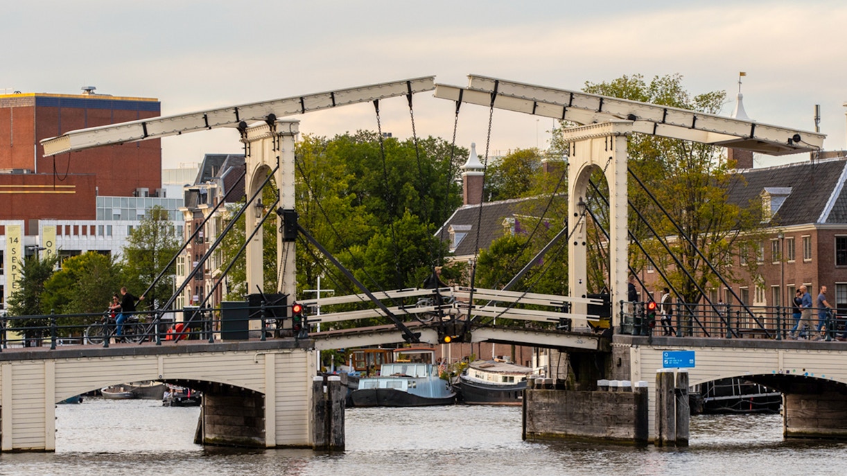 Amsterdam's Magere Brug over the Amstel River with boats passing underneath.