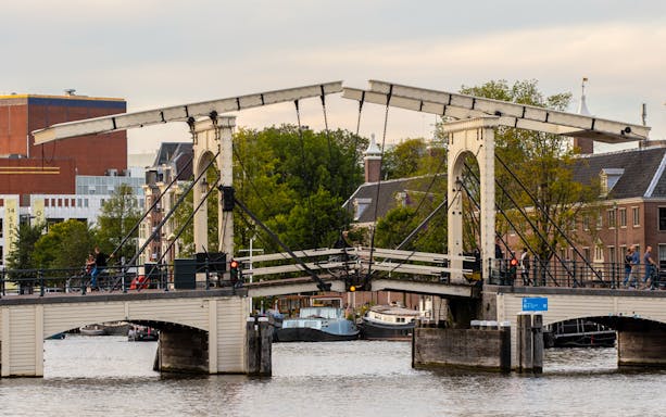 Amsterdam's Magere Brug over the Amstel River with boats passing underneath.