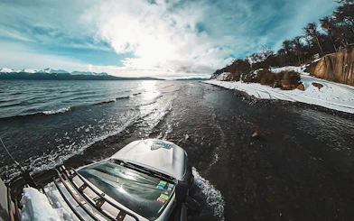 4x4 vehicle driving along the snowy shore of Lake Fagnano, Argentina.