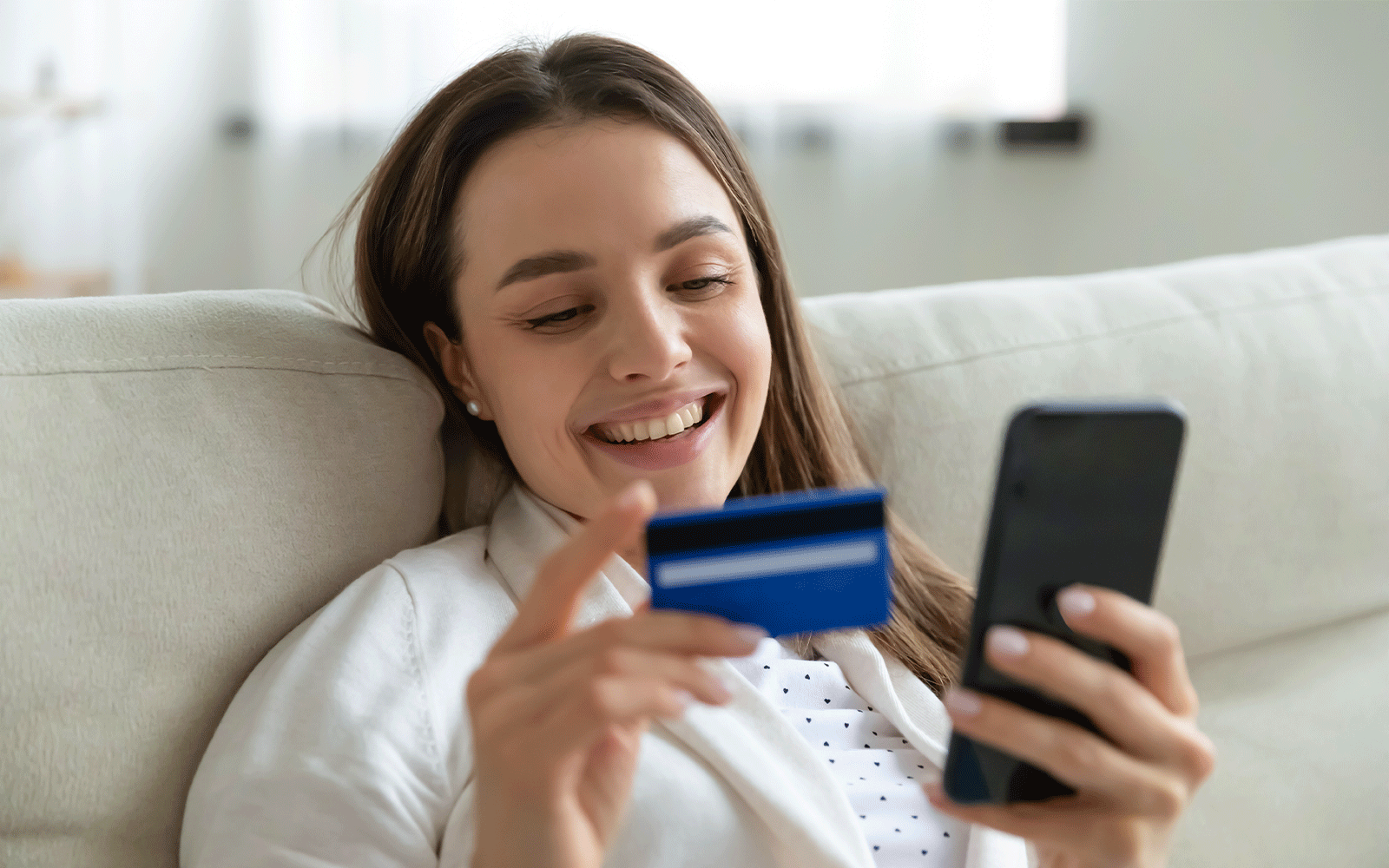 Young woman booking online with a banking card and smartphone.
