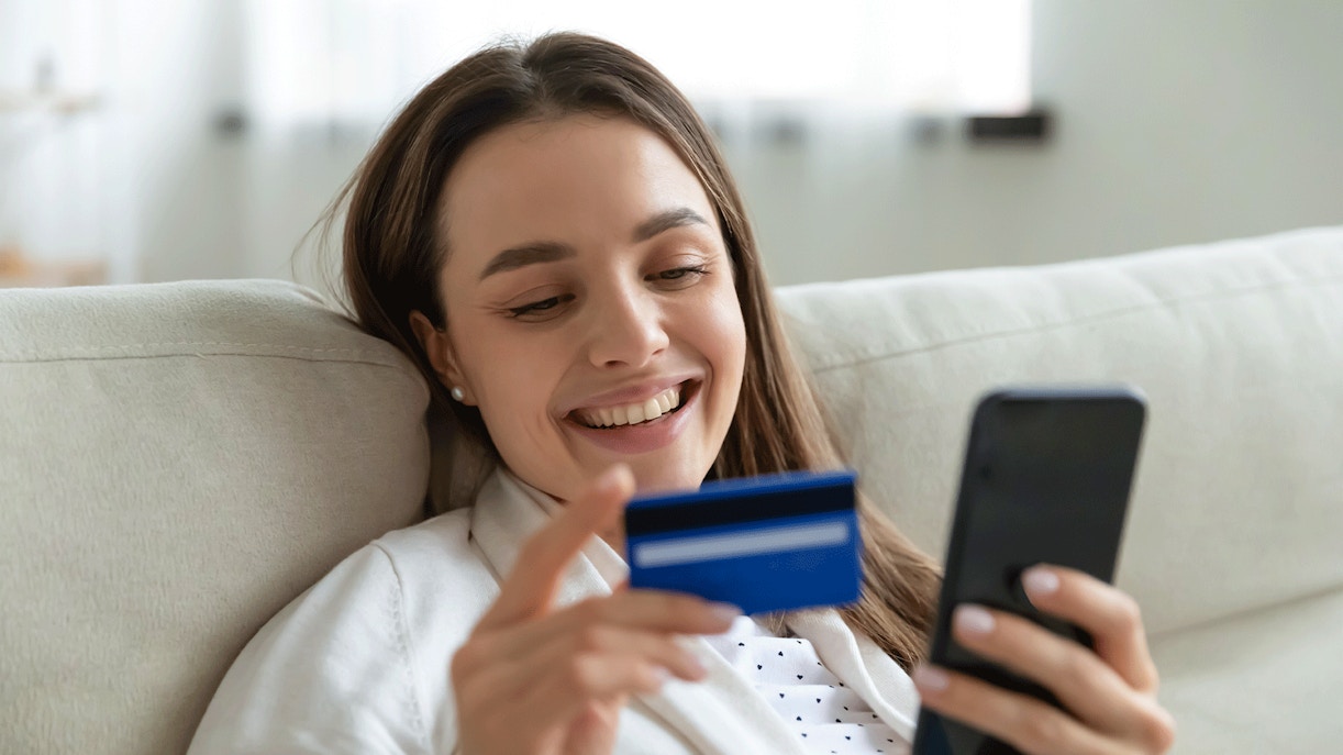 Young woman booking online with a banking card and smartphone.