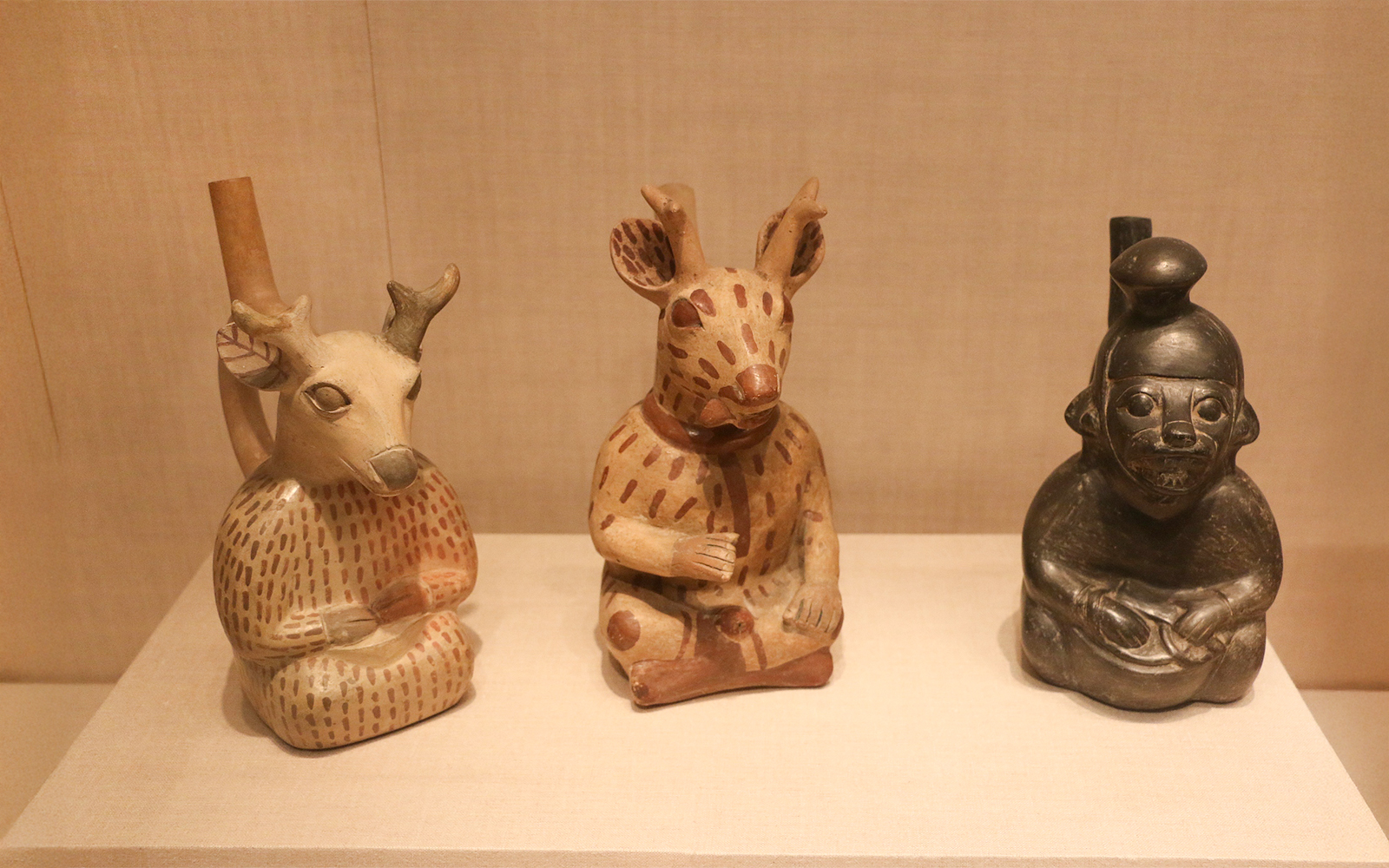 Three Moche ceramic vessels depicting animal and human forms at The Art Institute of Chicago.