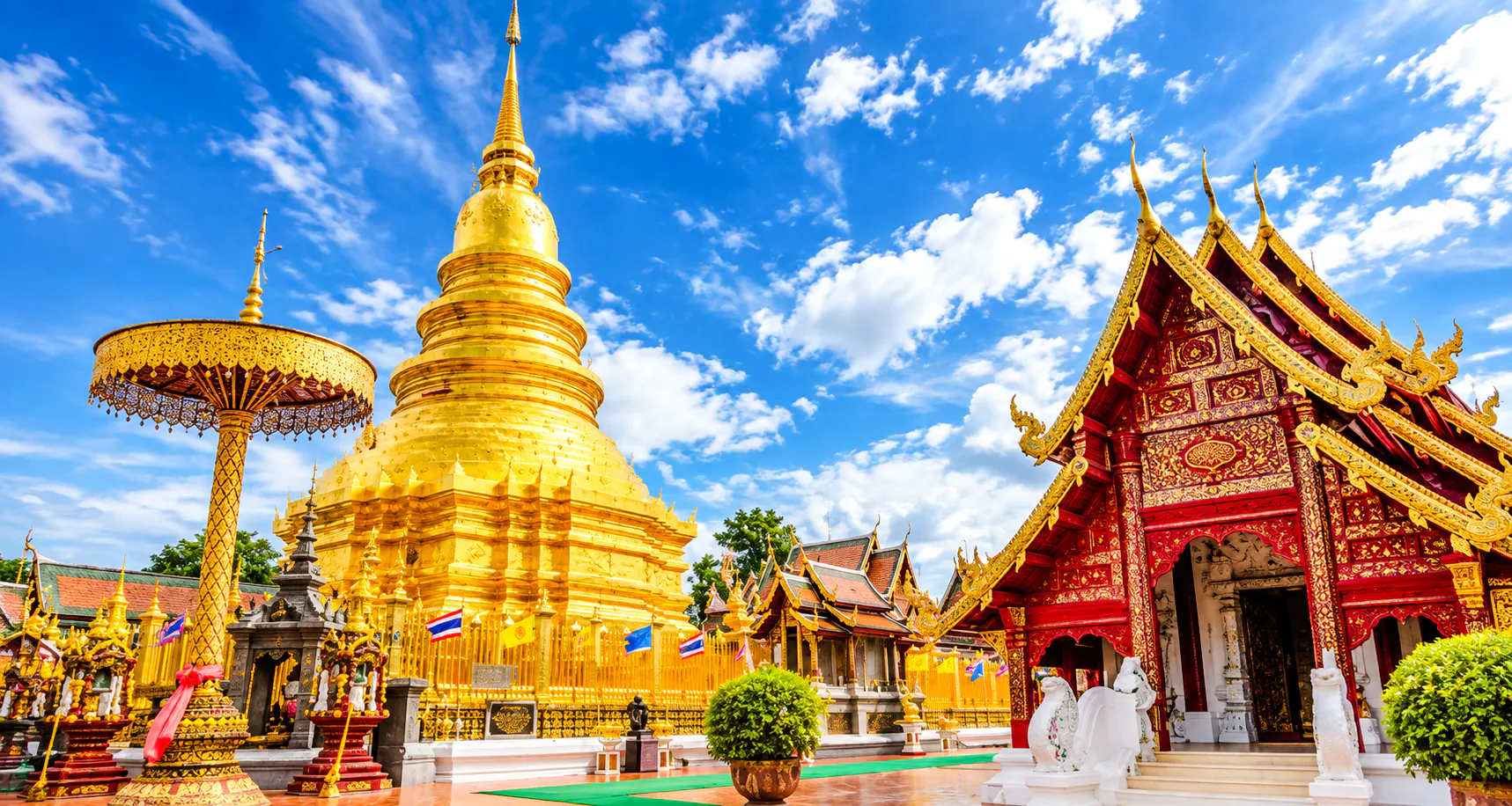 Golden pagoda and ornate temple in Chiang Mai under a blue sky.
