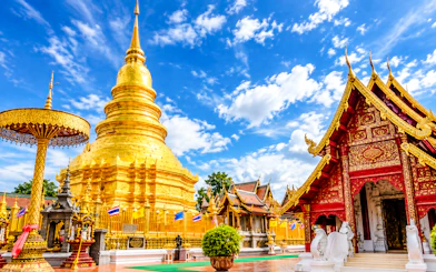 Golden pagoda and ornate temple in Chiang Mai under a blue sky.