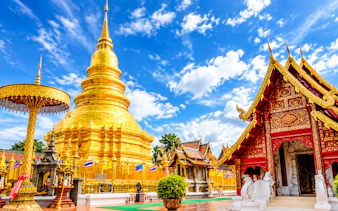 Golden pagoda and ornate temple in Chiang Mai under a blue sky.