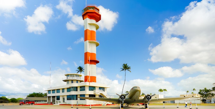 Pearl Harbor Aviation Museum exterior with control tower and vintage aircraft.