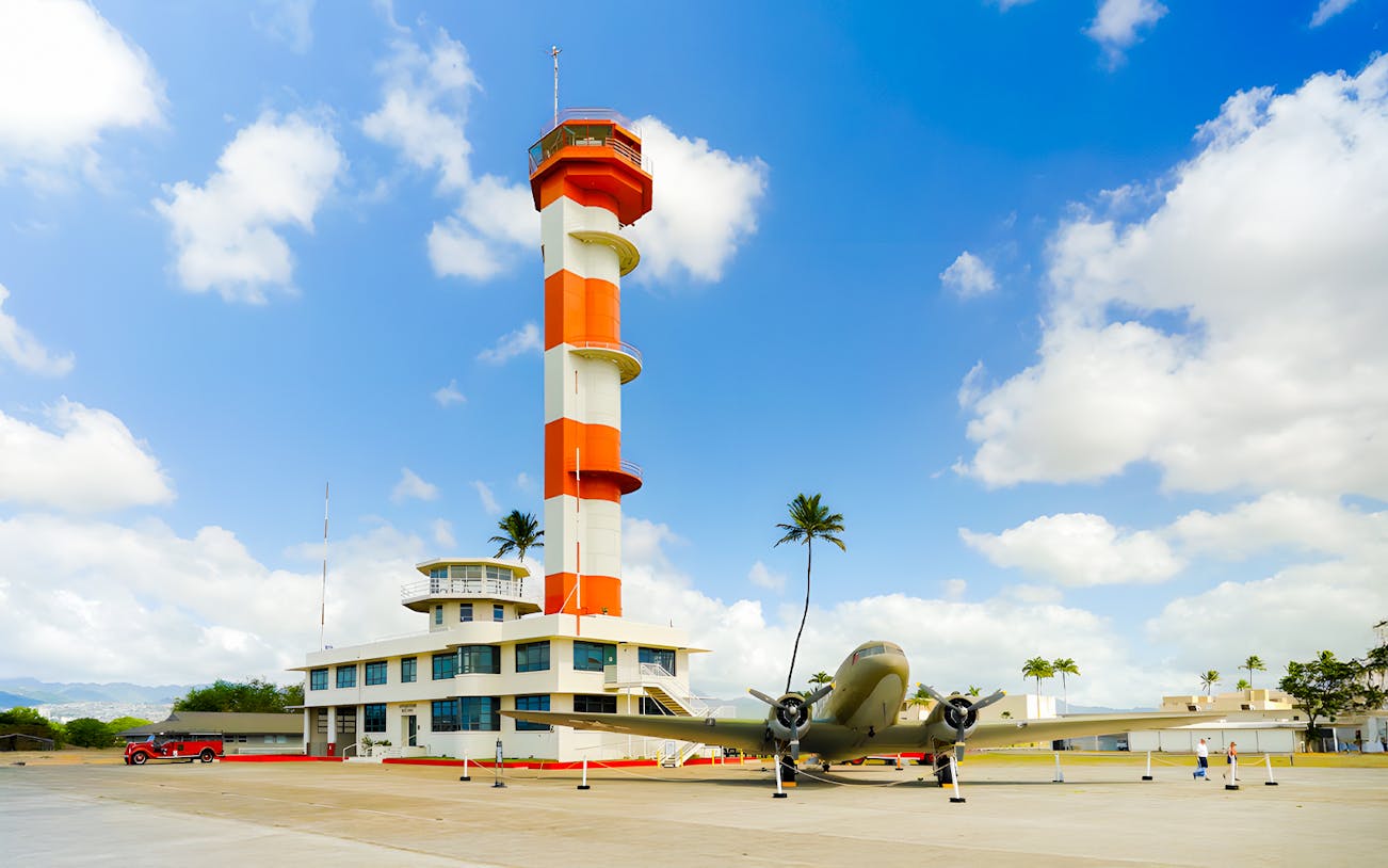 Pearl Harbor Aviation Museum exterior with control tower and vintage aircraft.