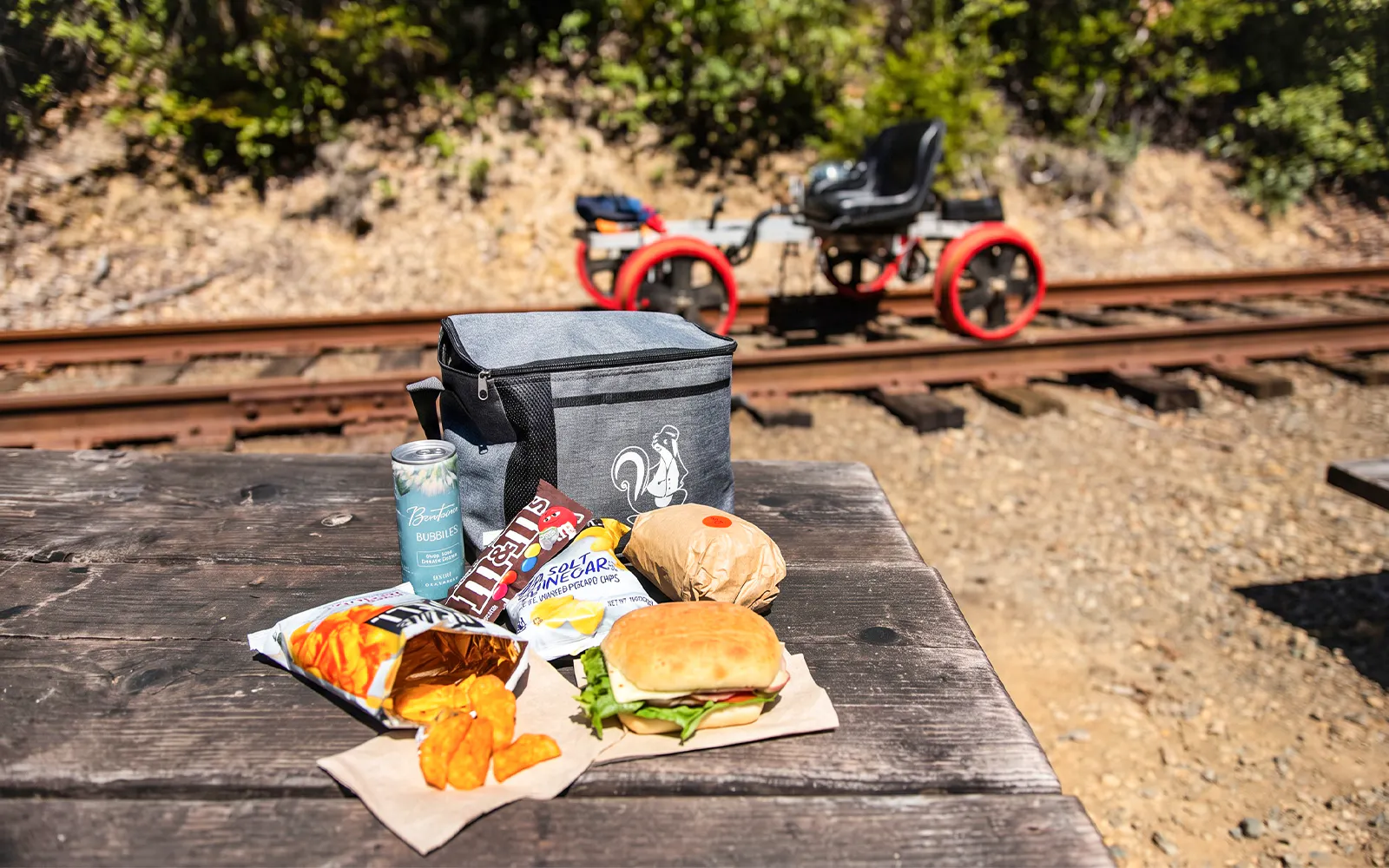 Picnic setup with snacks and drinks on a table near railway tracks in Noyo, San Francisco.