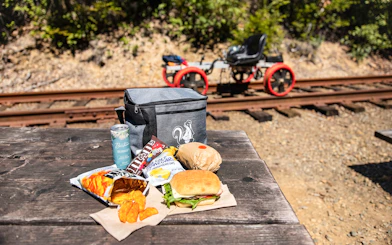 Picnic setup with snacks and drinks on a table near railway tracks in Noyo, San Francisco.