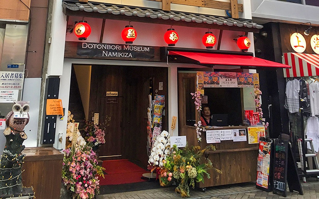 Entrance to Osaka Dotonbori Museum Namikiza with ticket booth and red lanterns.