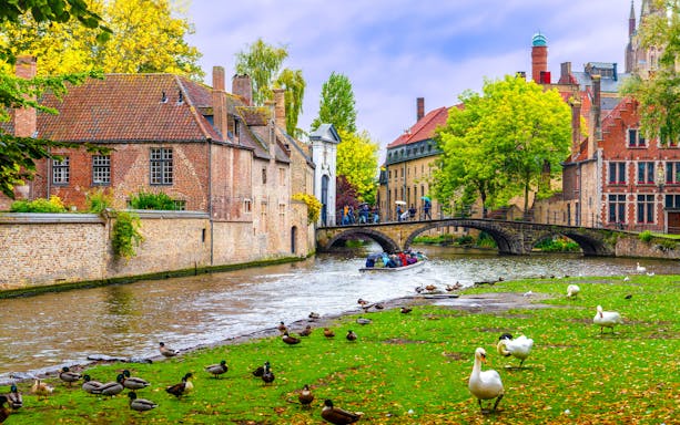 Stone bridge over Lake of Love with swans and tourists, near Begijnhof, Bruges, Belgium.