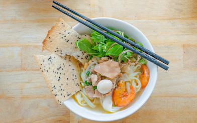 Vietnamese rice noodles with shrimp, herbs, and sesame crackers in a bowl.