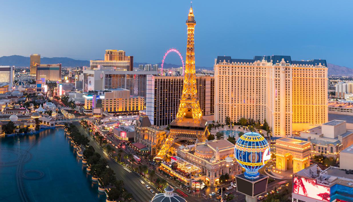 Eiffel Tower replica at Paris Las Vegas Hotel illuminated at dusk, with city skyline.