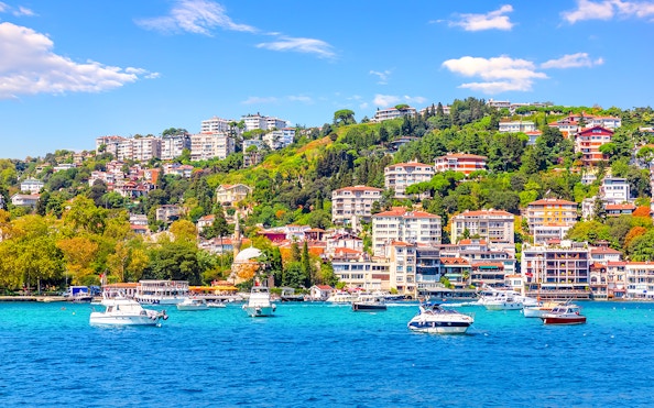Boats on the Bosphorus with Bebek district hillside in Istanbul.
