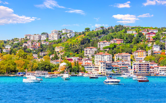 Boats on the Bosphorus with Bebek district hillside in Istanbul.