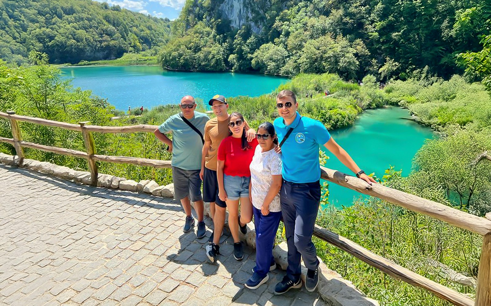 Guests standing by a turquoise lake at Plitvice Lakes National Park, Croatia.