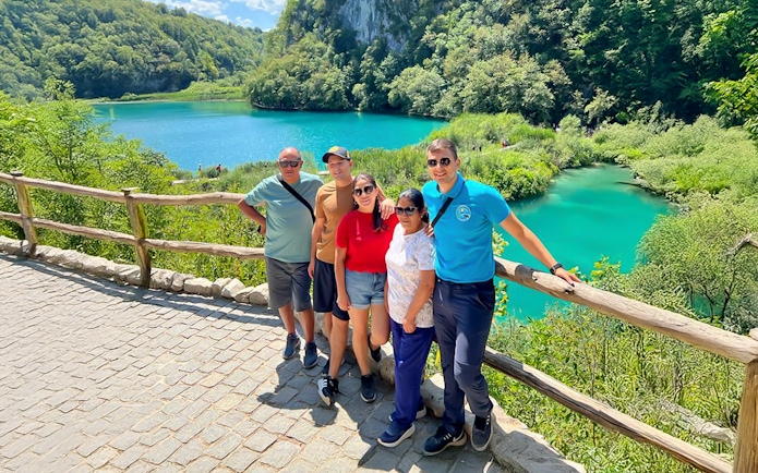 Guests standing by a turquoise lake at Plitvice Lakes National Park, Croatia.