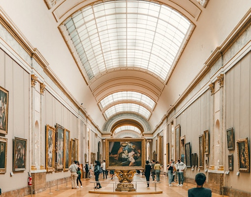 Louvre Museum entrance with Inverted Pyramid and visitors exploring the courtyard in Paris.