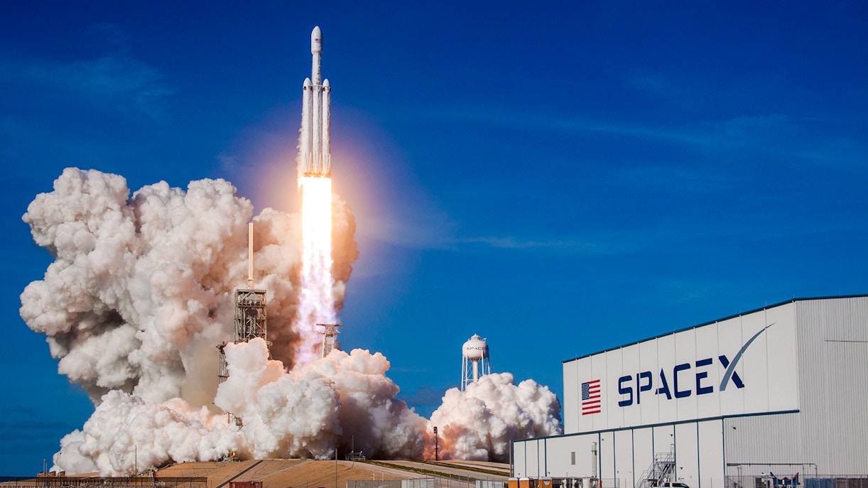 SpaceX Falcon Heavy rocket launching at night with bright flames and smoke.