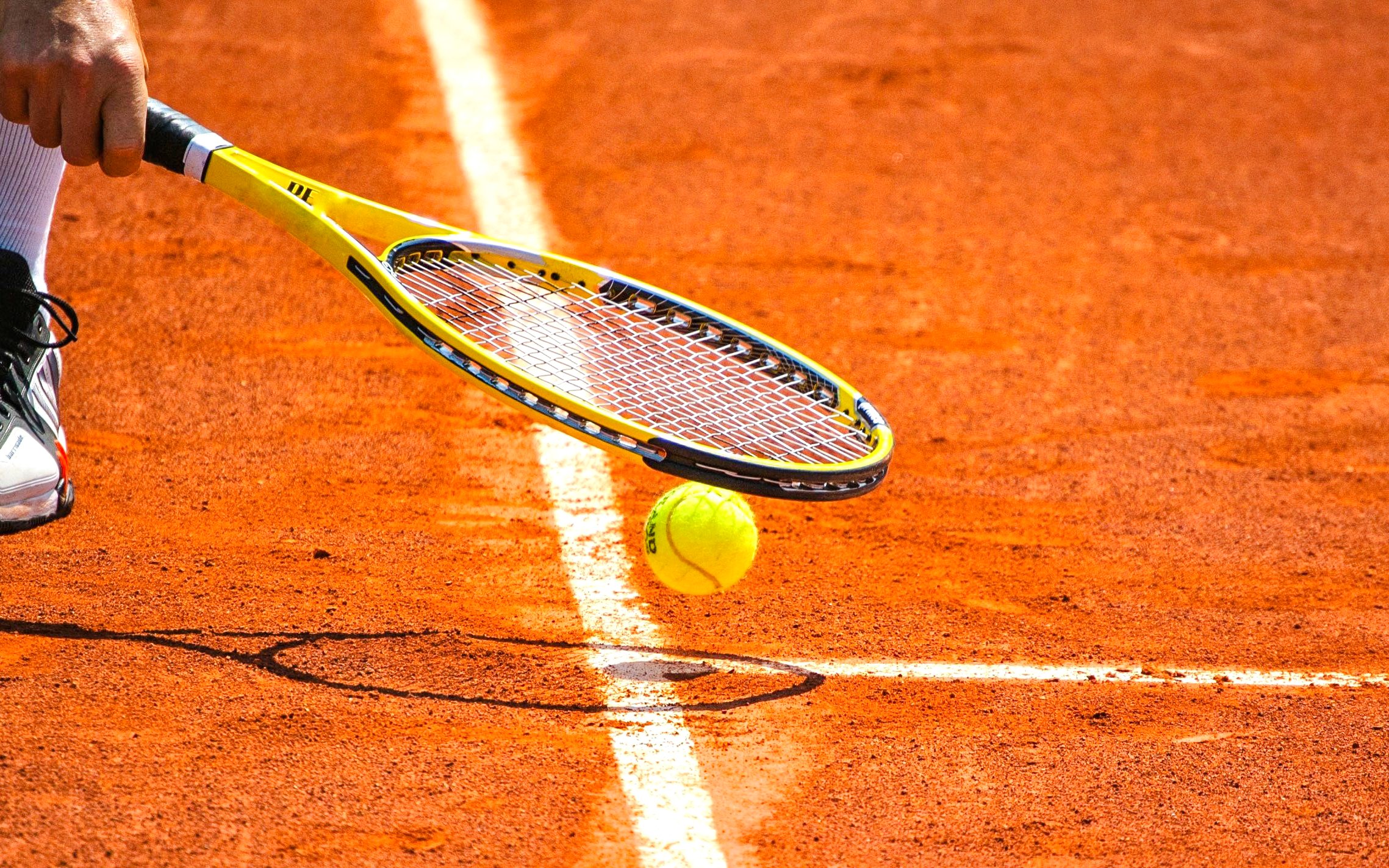 Tennis ball and racket on clay court at Roland-Garros Stadium.