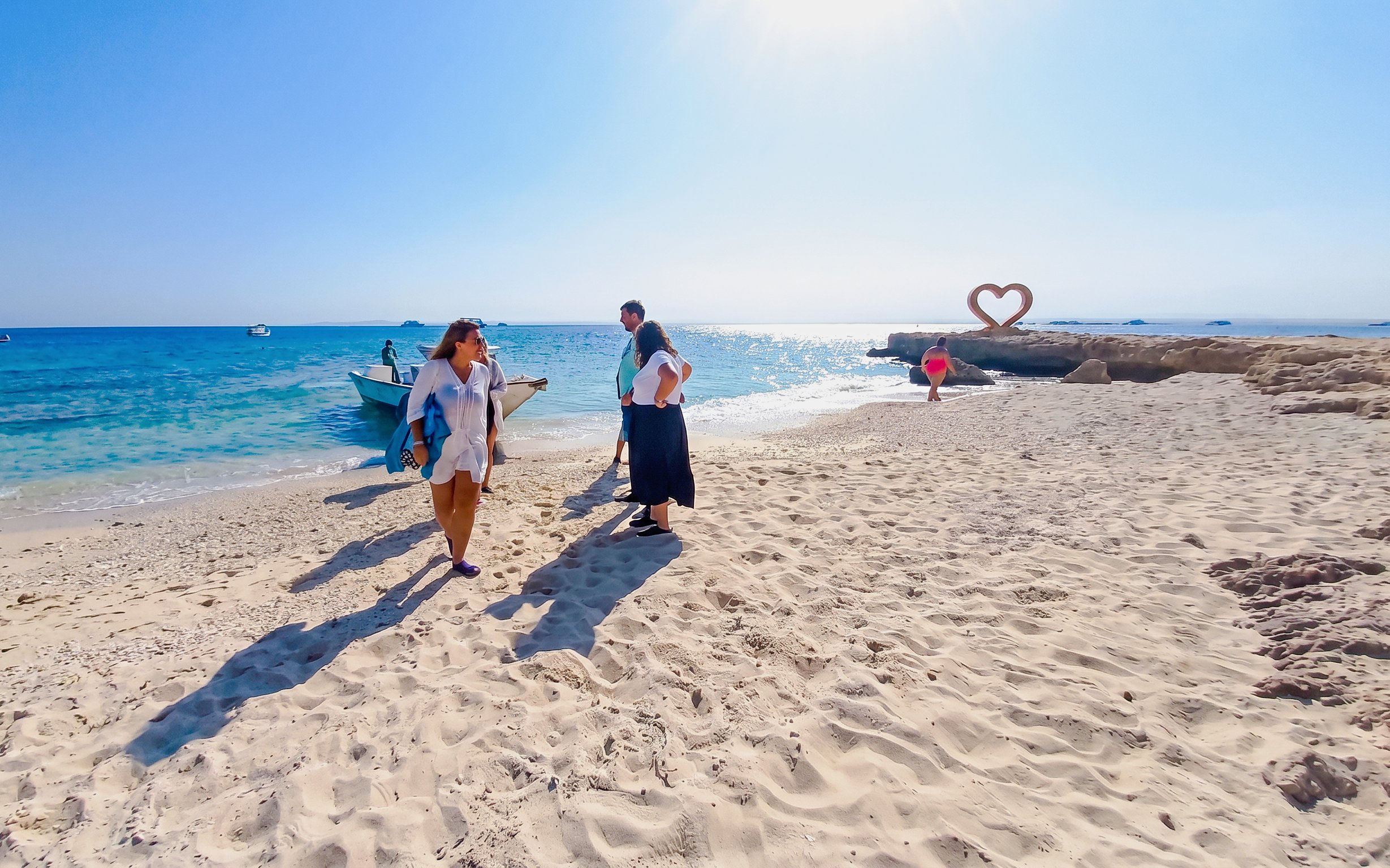 Tourists on a sandy beach near a boat during a high-speed sea taxi tour to Orange Bay.
