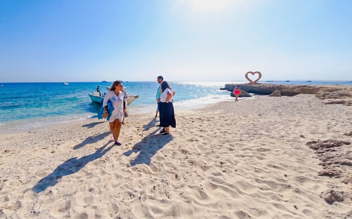 Tourists on a sandy beach near a boat during a high-speed sea taxi tour to Orange Bay.
