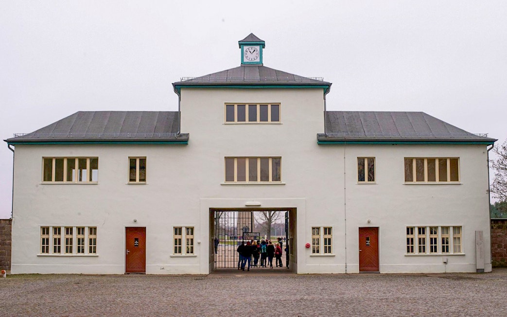 Main entrance of Sachsenhausen Concentration Camp with visitors entering through the gate.
