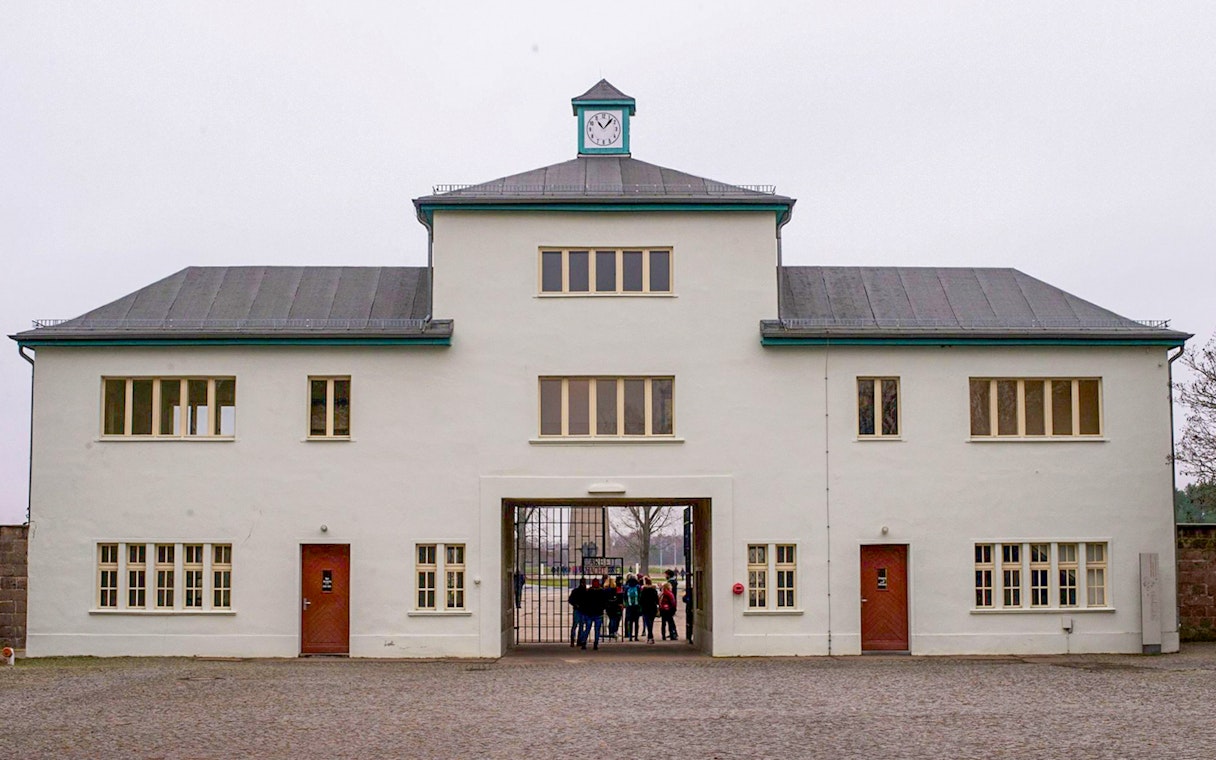 Main entrance of Sachsenhausen Concentration Camp with visitors entering through the gate.
