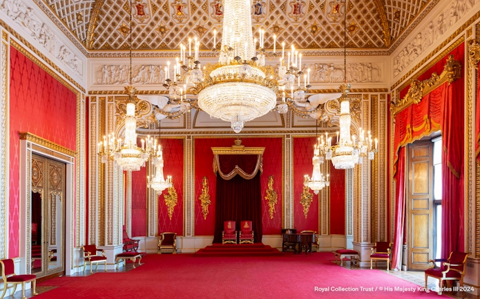 Throne Room at Buckingham Palace with ornate chandeliers and red decor.