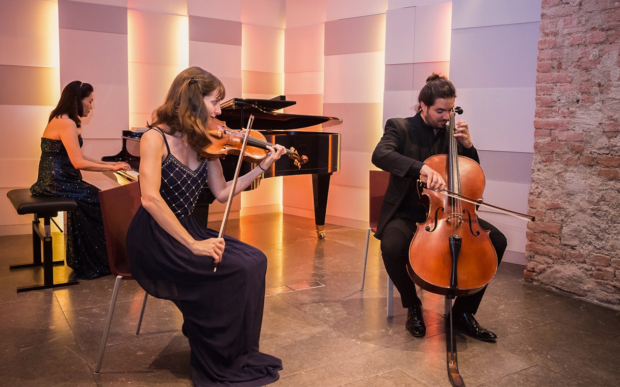 Musicians performing with violin, cello, and piano at Mozarthaus concert in Vienna.