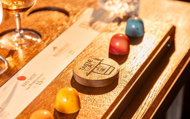 Jameson whiskey and colorful chocolates on a tasting board in a Dublin bar.