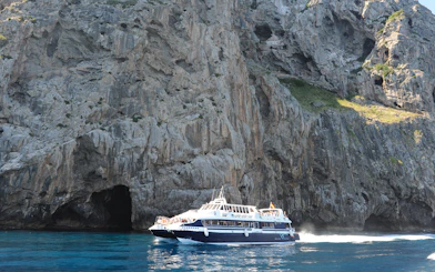 Boat cruising near rocky cliffs on Mallorca sightseeing tour.