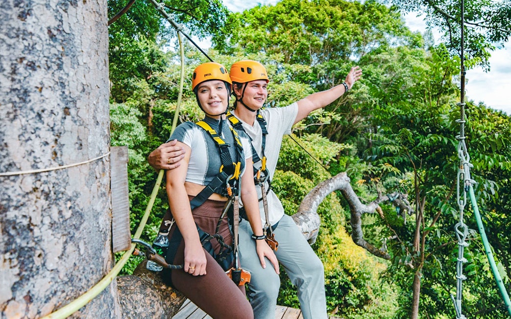 Participants on a zipline platform at Flying Hanuman, Phuket, wearing safety gear amidst lush forest.