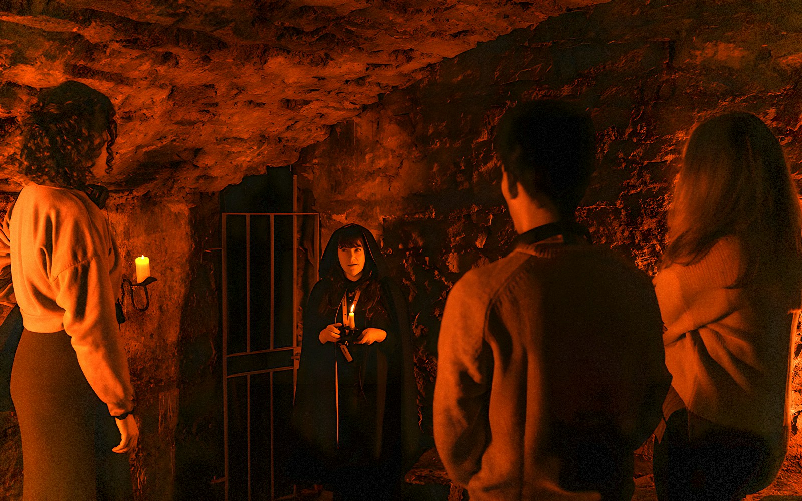 Tour guide in cloak leading group in Edinburgh underground vaults.