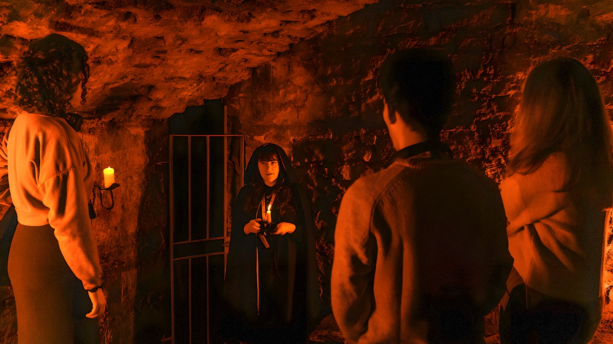 Tour guide in cloak leading group in Edinburgh underground vaults.