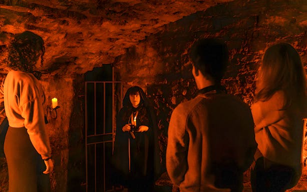 Guide narrating ghost stories to a group during an underground ghost tour in Edinburgh