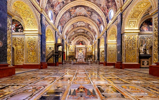 Interior of St. John's Co-Cathedral in Valletta, featuring ornate gold decorations and detailed frescoes.