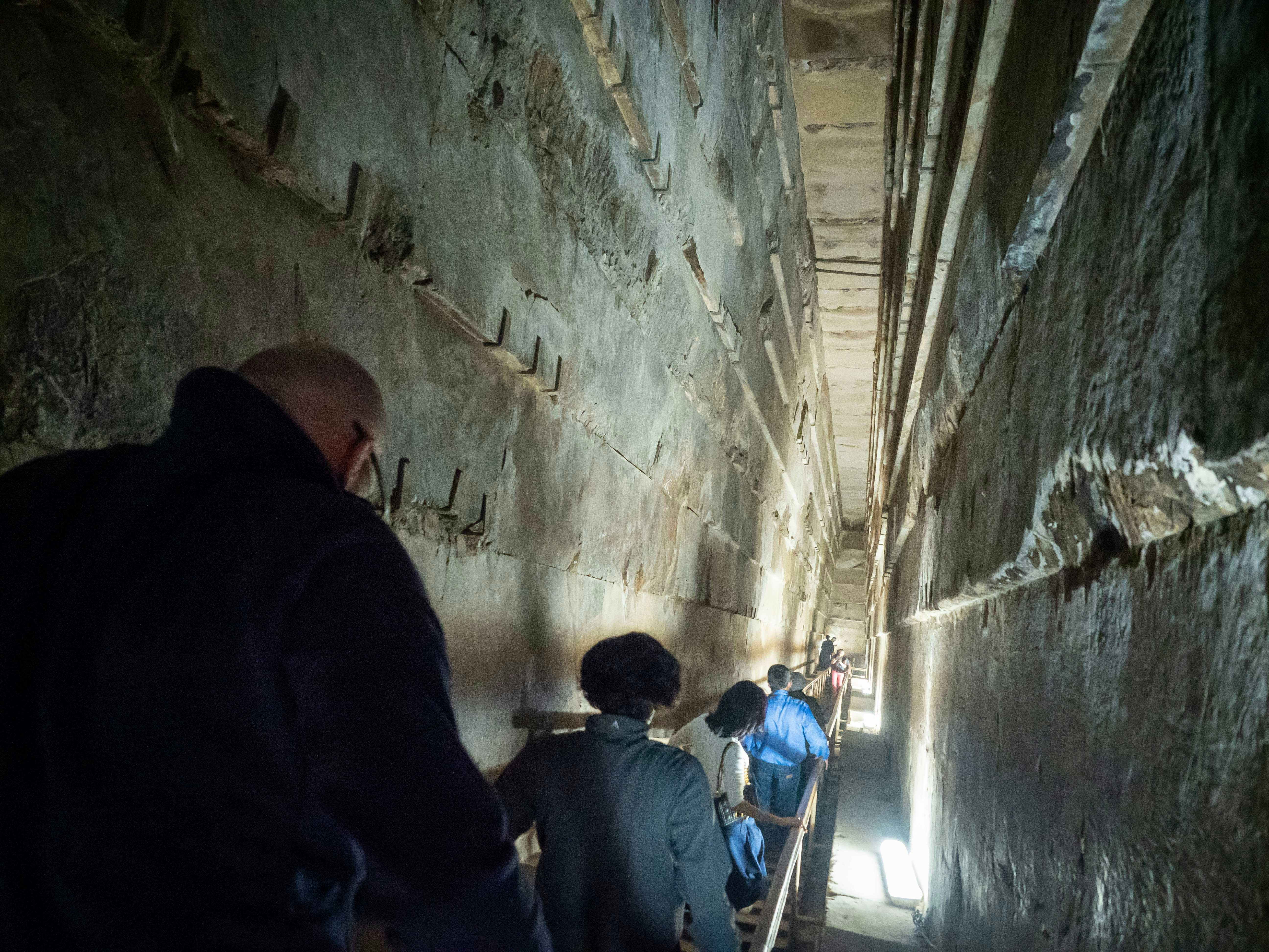 Visitors exploring narrow passage inside the Pyramids of Giza, Egypt.