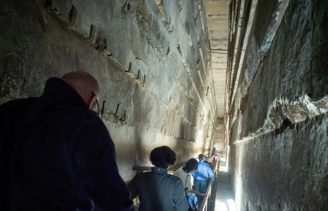 Visitors exploring narrow passage inside the Pyramids of Giza, Egypt.