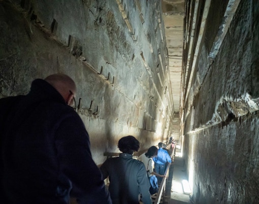 Visitors exploring narrow passage inside the Pyramids of Giza, Egypt.