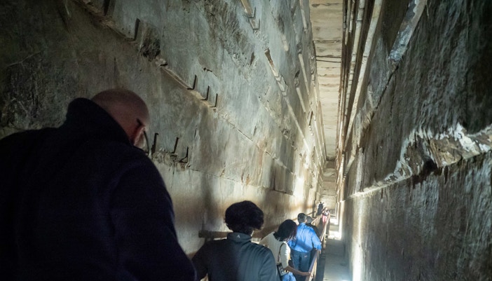 Visitors exploring narrow passage inside the Pyramids of Giza, Egypt.