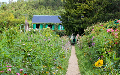 Pathway through Monet's garden leading to his house in Giverny, surrounded by vibrant flowers.