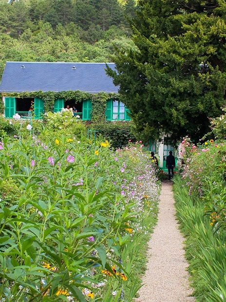 Pathway through Monet's garden leading to his house in Giverny, surrounded by vibrant flowers.