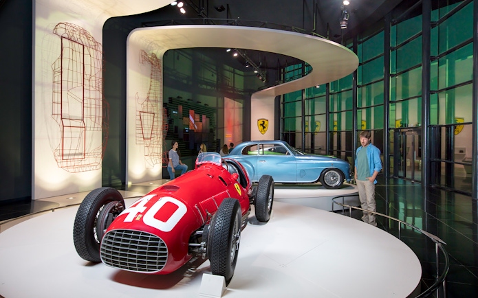 Man observing classic Ferrari cars in Ferrari Land exhibit.