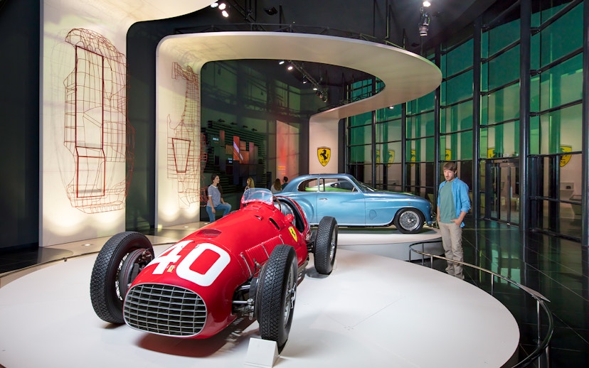 Man observing classic Ferrari cars in Ferrari Land exhibit.