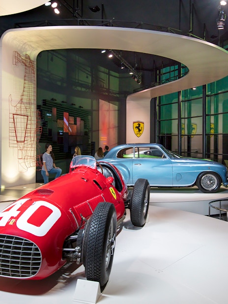 Man observing classic Ferrari cars in Ferrari Land exhibit.