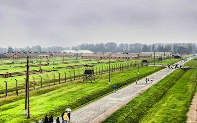 Auschwitz Birkenau II watchtower overlooking barracks and visitors walking along the path.