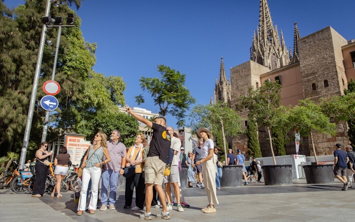 Tourists exploring the Gothic Quarter in Barcelona with the Barcelona Cathedral in the background.