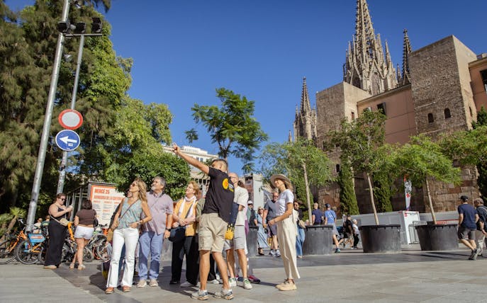 Tourists exploring the Gothic Quarter in Barcelona with the Barcelona Cathedral in the background.