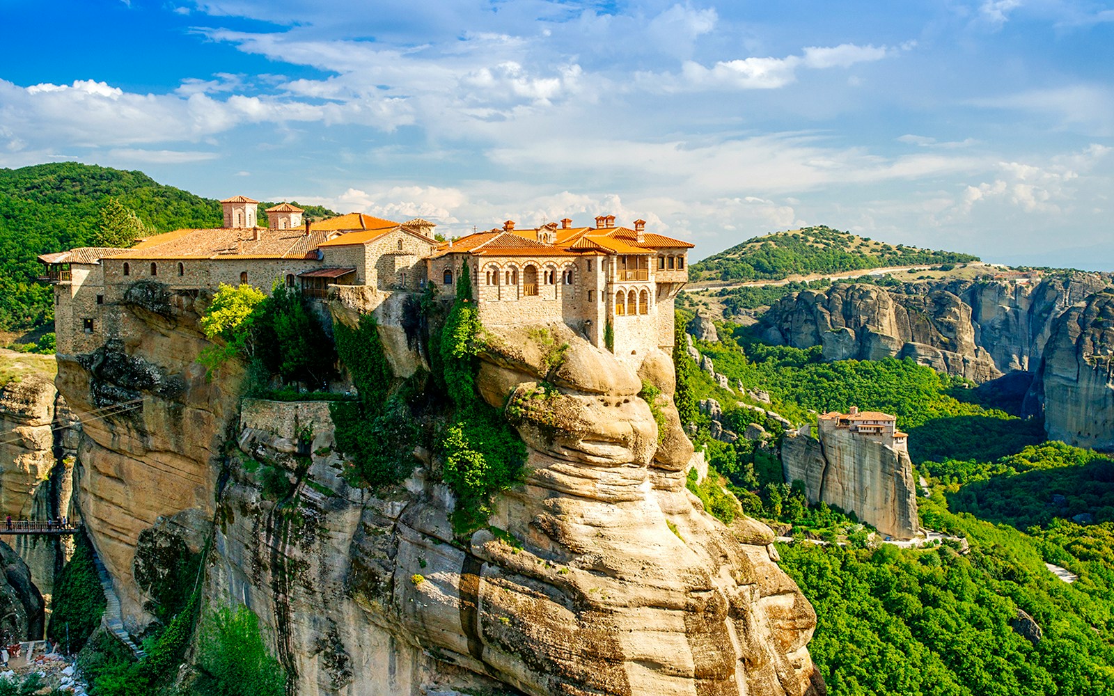 Meteora monastery perched on a rock formation in Greece, surrounded by lush green landscape.